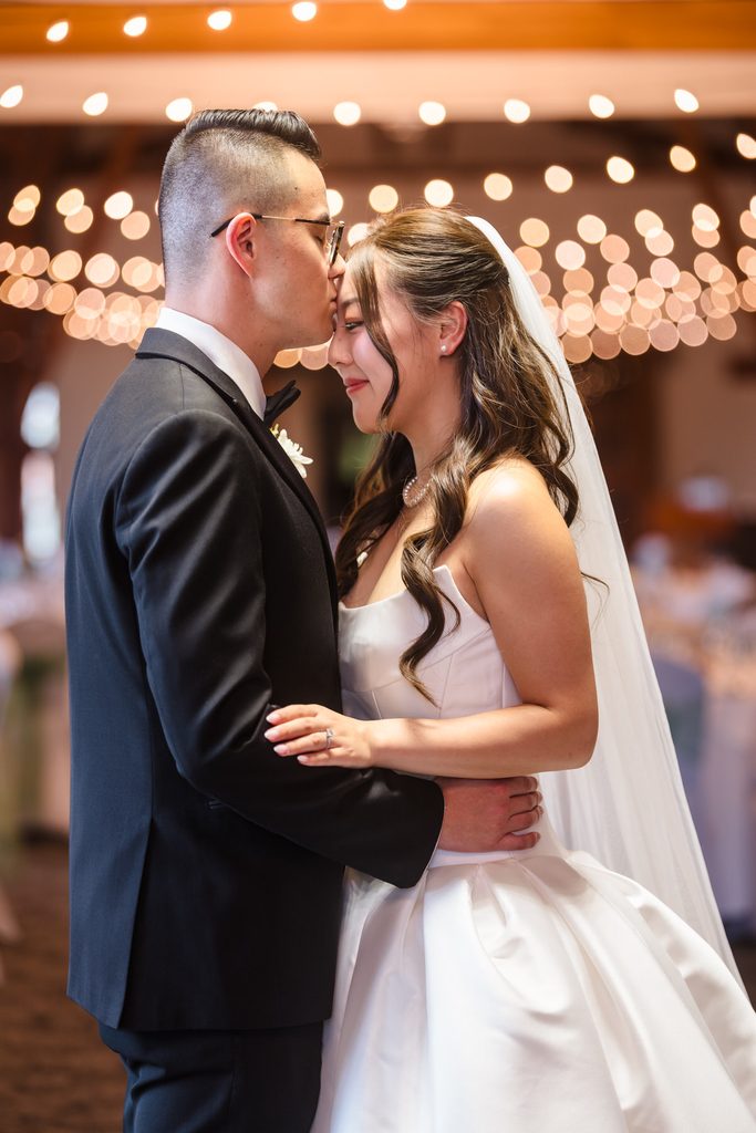 The couple embraces beneath the string lights at the reception room entrance