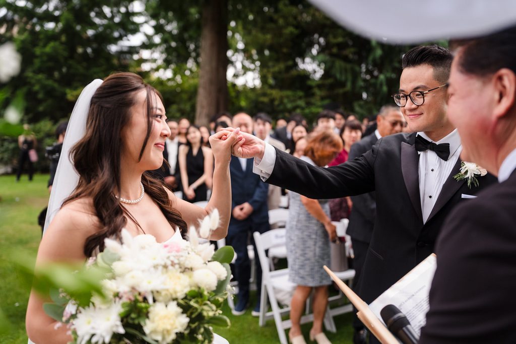 The bride and groom touch hands in front of the officiant.