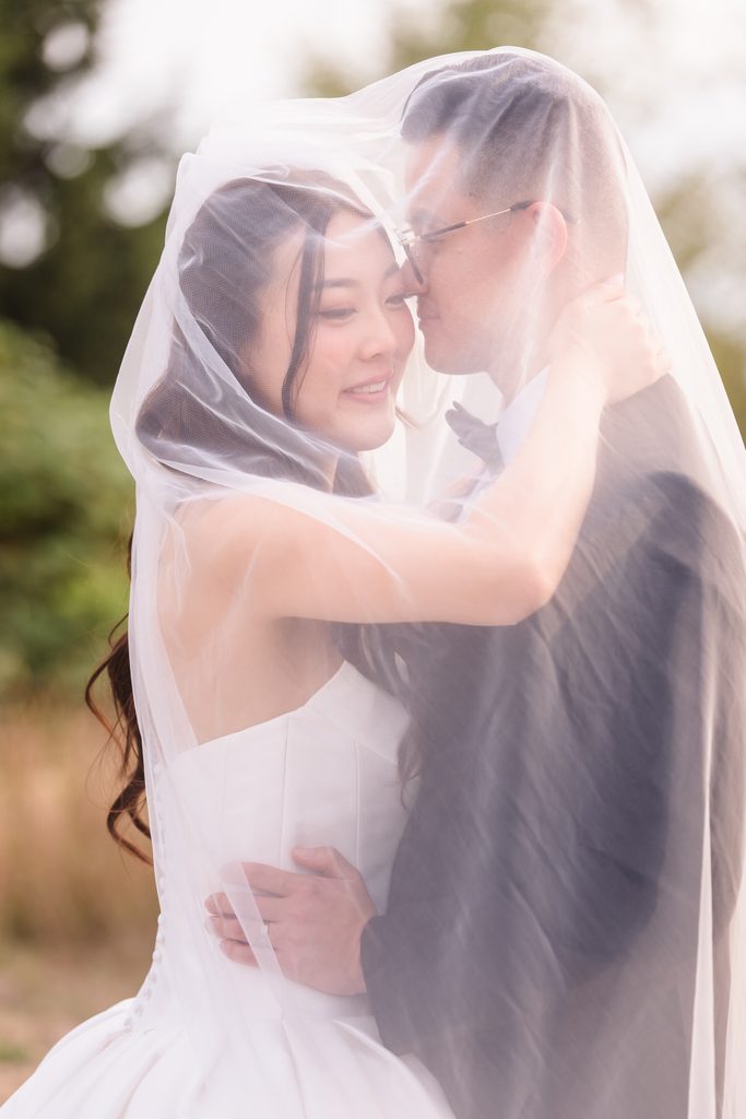 The bride rests her hand on the groom's chest in this black and white veil portrait.