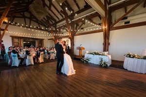The couple hold each other close on the dance floor as evening sets in first dance underneath the string lights with their guest in the background.