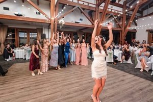 The bride raises her arms as the bouquet sails above the waiting guests.